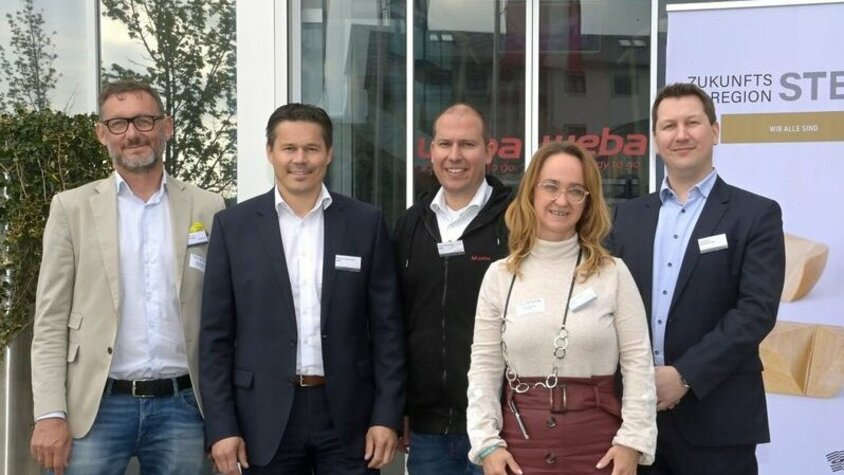 Gruppenfoto der Veranstaltenden des Stammtisches 4.0 Zukunftsregion Steyr vorm Gebäudeeingang bei bei weba Werkzeugbau; rechts im Hintergrund ist das Roll-up der Zukunftsregion zu sehen 