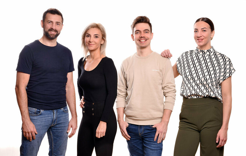 Two female and two male employees of weba Werkzeugbau stand side by side, smiling warmly at the camera. They appear relaxed and confident, reflecting a positive work environment. Job opportunities in Steyr for experienced professionals at weba Werkzeugbau within a strong team community.