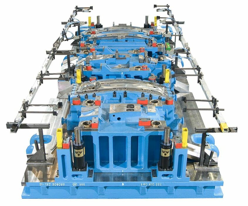 A detailed illustration of a blue transfer tool for cold forming including a transfer gripper rail for the production of B-pillars for vehicles, visualized on a neutral background. Particular attention is paid to the transfer gripper rail, which is precisely designed for handling and transporting the B-pillars within the production line. The design of the tool demonstrates a high level of engineering skill, with visible details that illustrate the functionality and efficiency of the system within automotive production. It also demonstrates weba's expertise in toolmaking and forming technology.