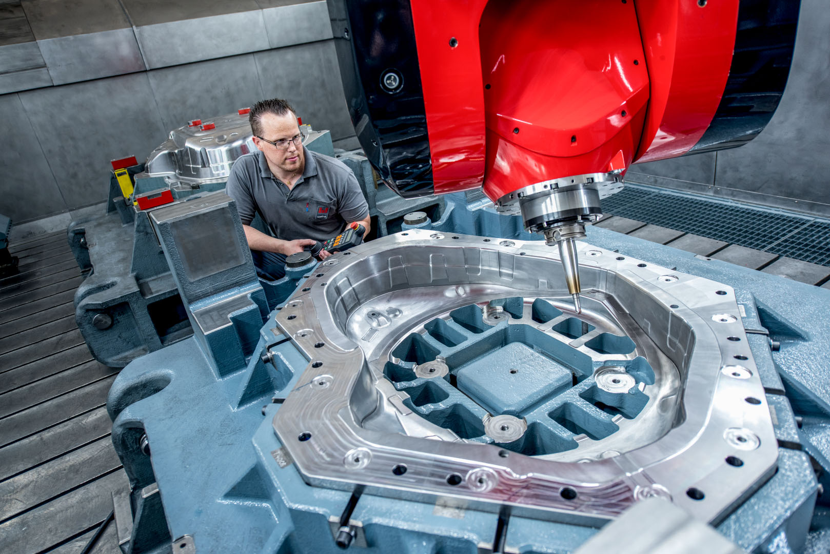 A Skilled Worker Operates a State-of-the-Art CNC Milling Machine with a Large Tool Component  The shiny metal surface of the component reflects precise machining results, while the red milling unit is prominently displayed in the foreground.